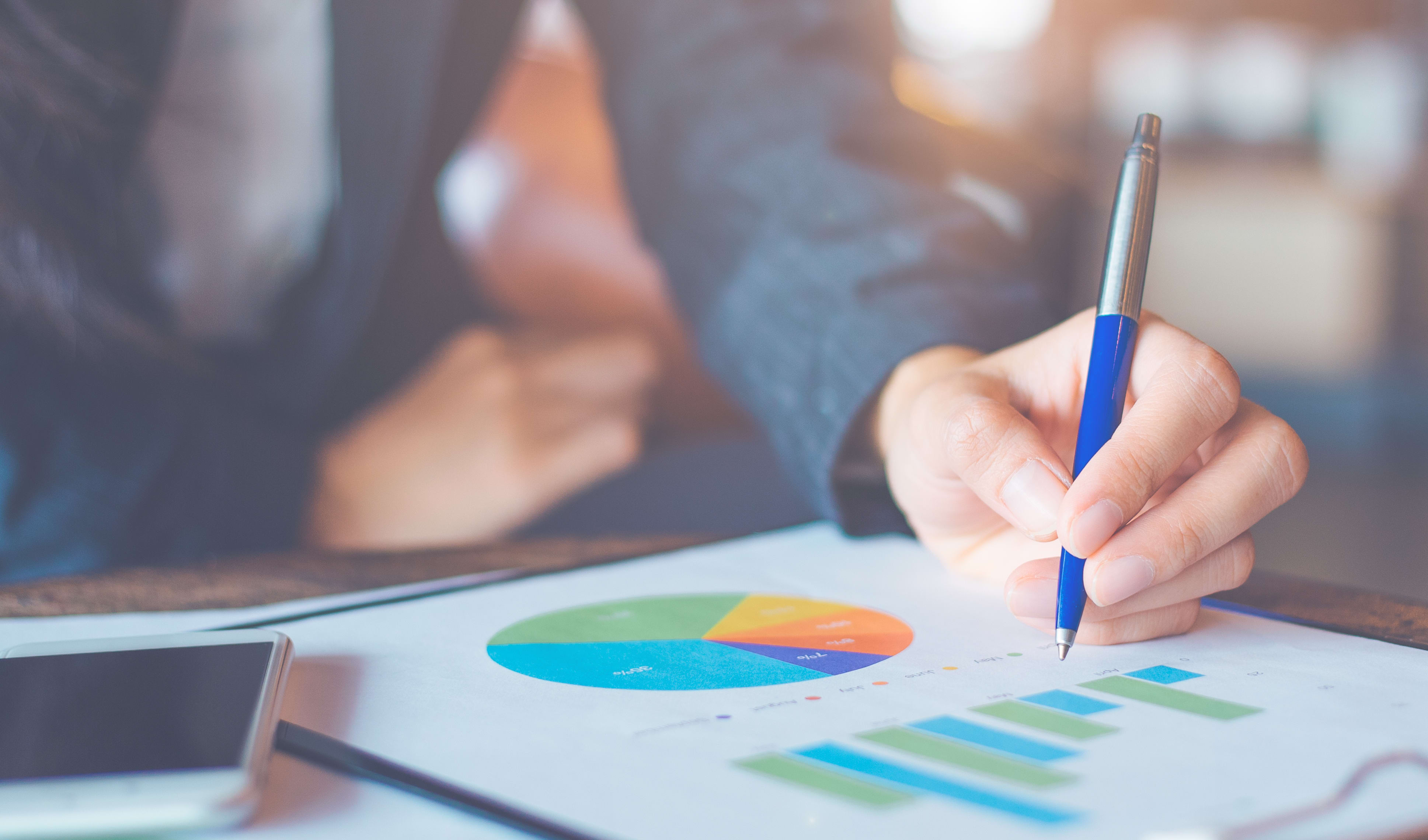 Business woman hand writing on charts and graphs that show results.