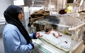 A medical worker stands by a prematurely born baby lying in an infant incubator at the neonatal intensive care unit (NICU) of Nasser Medical Complex, currently at risk due to dwindling fuel supplies, in Khan Yunis in the southern Gaza Strip on January 13, 2025 amid the ongoing war in the Palestinian territory between Israel and Hamas.