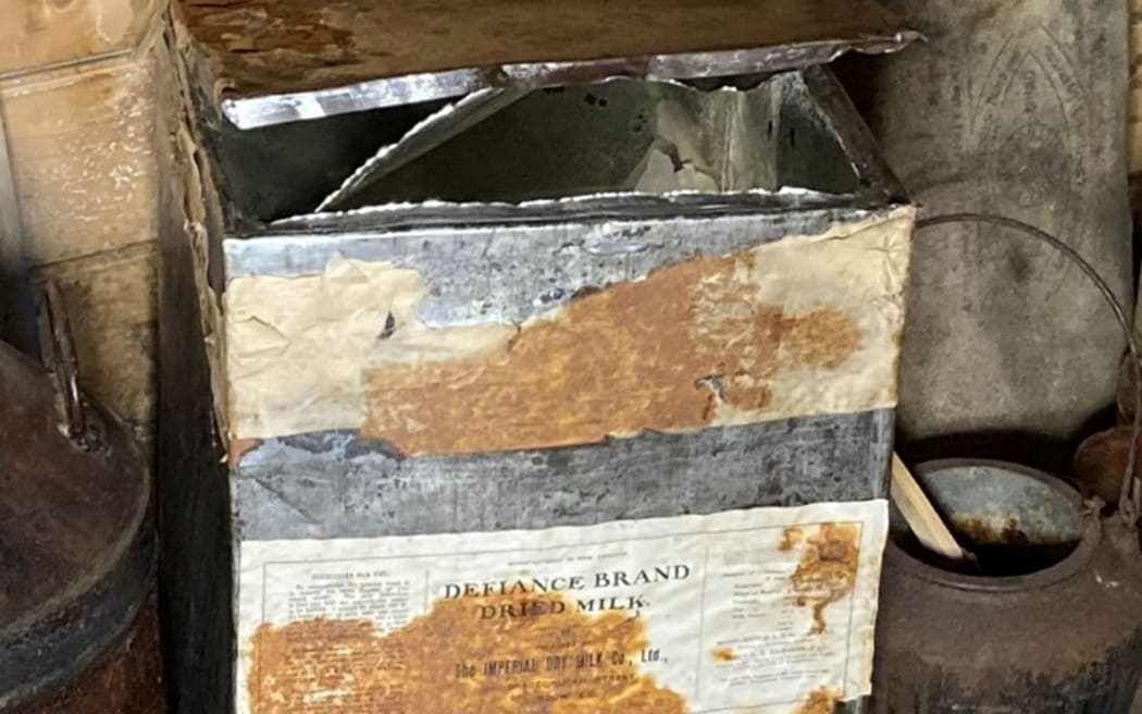 An old box holding milk powder. The paper labels around the tin are faded and stained. 