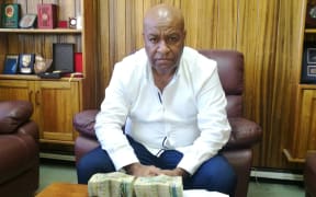 Senior Sergeant Apollo Terry with the K100,000 kina cash bribe. On the right of the picture is the K6,500 cash found on policeman.