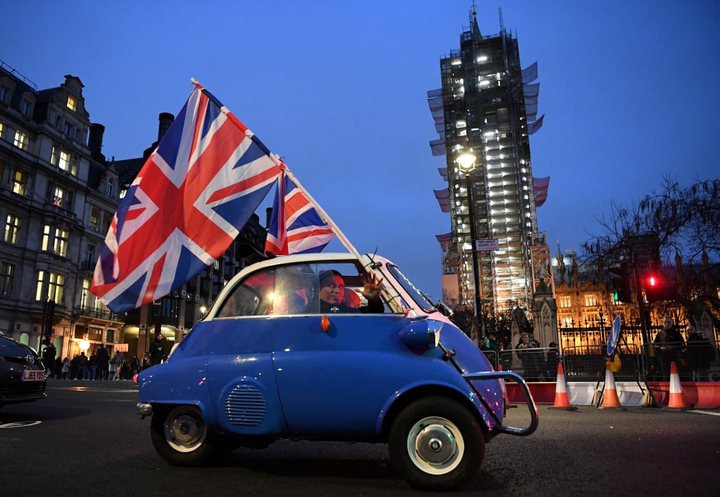 A man waves Union flags from a small car as he drives past Brexit supporters gathering in Parliament Square, near the Houses of Parliament in central London on Brexit day.