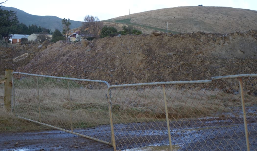 The quarried dirt 'overburden' dumped in large piles in front of the quarry pit.