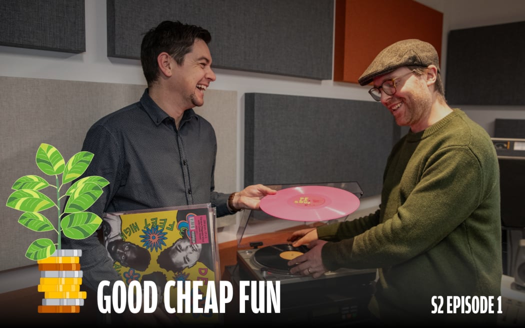 An image of two young men laughing together as they select records to play on a turntable.