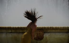 A woman refreshes herself in a fountain at Plaza de Espana, on a hot summer day in Sevilla, Spain.