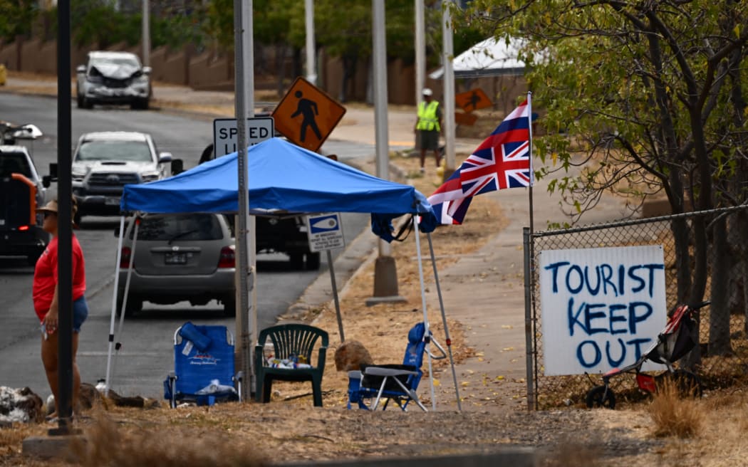 The Flag of Hawaii waves by a sign reading "Tourist Keep Out" in the aftermath of the Maui wildfires in Lahaina, Hawaii.