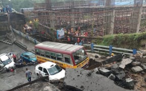 Indian rescue teams and onlookers stand on rubble and atop Majerhat bridge after a segment of the bridge suddenty collapsed in Kolkata in the Indian state of West Bengal.