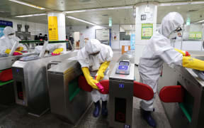Workers wearing protective gear disinfect ticket gates as part of preventive measures against the spread of the Covid-19 coronavirus, at a subway station in Seoul on February 28, 2020.