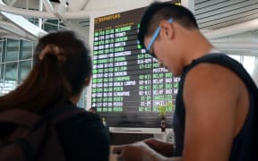 Passengers check flight information in the international terminal at Bali's Ngurah Rai airport in Denpasar.