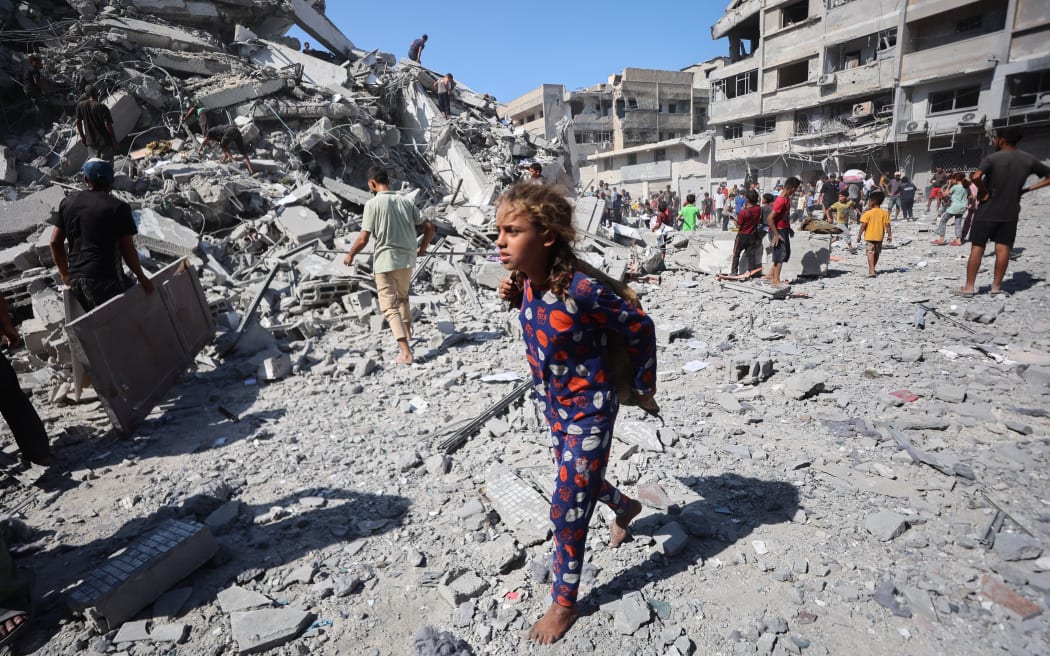 Displaced Palestinians salvage items from the rubble of the al-Ghafari tower after it was destroyed in Israeli strikes in Gaza City.