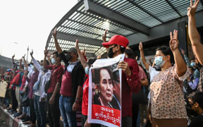 Protesters hold up the three finger salute and placards during a demonstration against the military coup in Yangon on February 7, 2021. (Photo by YE AUNG THU / AFP)