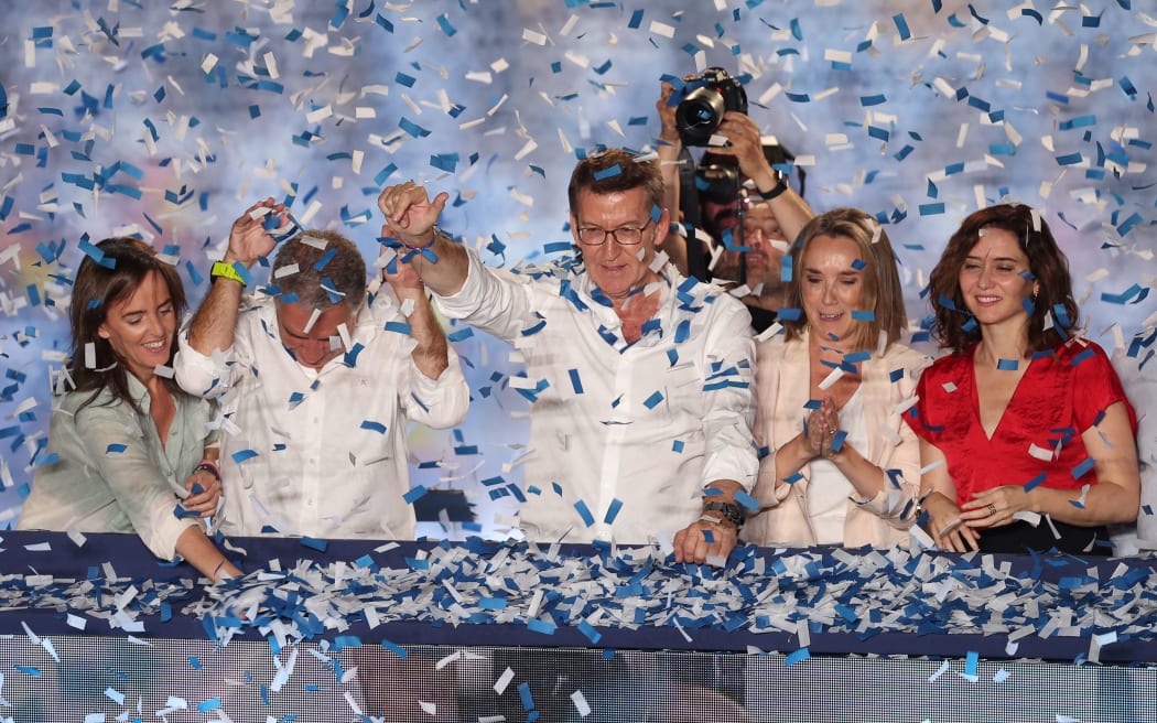 The conservative Partido Popular (People's Party) leader Alberto Nunez Feijoo, centre, waves to supporters next to Madrid regional president Isabel Diaz Ayuso, right, from a balcony of the PP headquarters in Madrid after Spain's general election on 23 July, 2023.