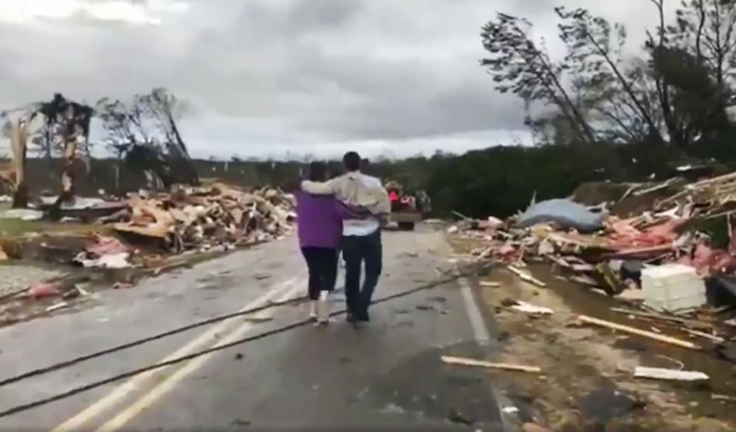 People walk amid debris in Lee County, Ala., after what appeared to be a tornado struck in the area Sunday, March 3, 2019.