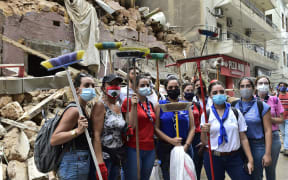 BEIRUT, LEBANON - AUGUST 07: People help to clean debris after a fire at a warehouse with explosives at the Port of Beirut led to massive blasts in Beirut, Lebanon on August 07, 2020.