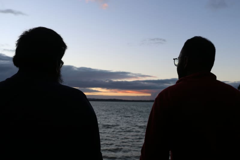 Two Muslims looking out at the coastal horizon during sunset at Point Chevalier's Coyle Park.