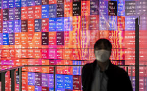 A man stands in front of an electronic share price board showing the numbers of the Tokyo Stock Exchange in Tokyo on February 25, 2022. (Photo by Charly TRIBALLEAU / AFP)