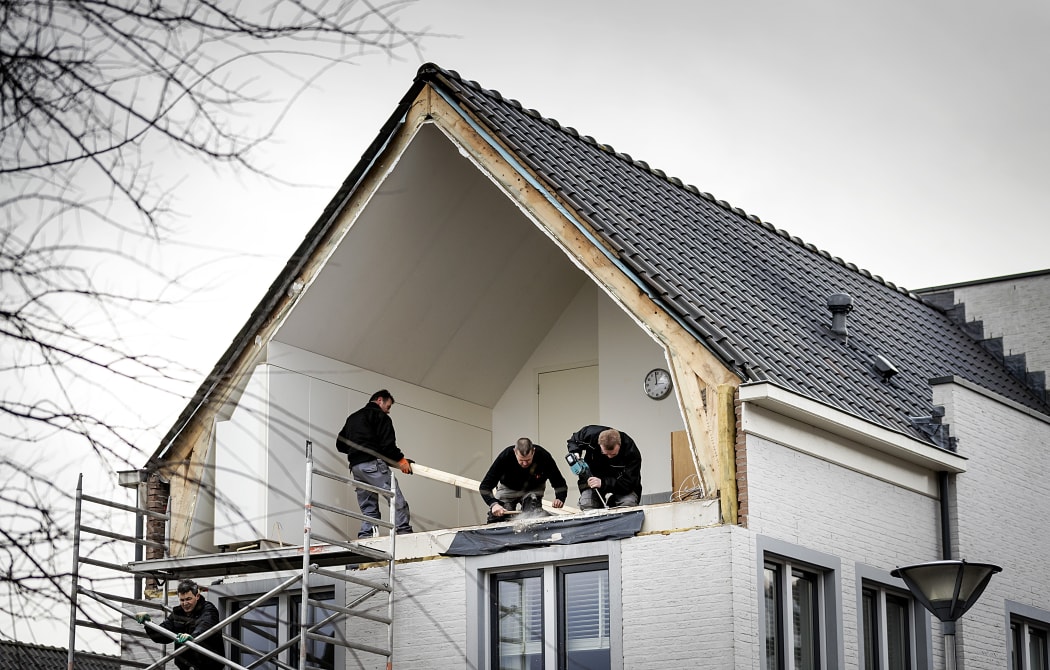 Builders fix the side wall of a house after it was blown away by windstorms in De Meern on January 18, 2018.