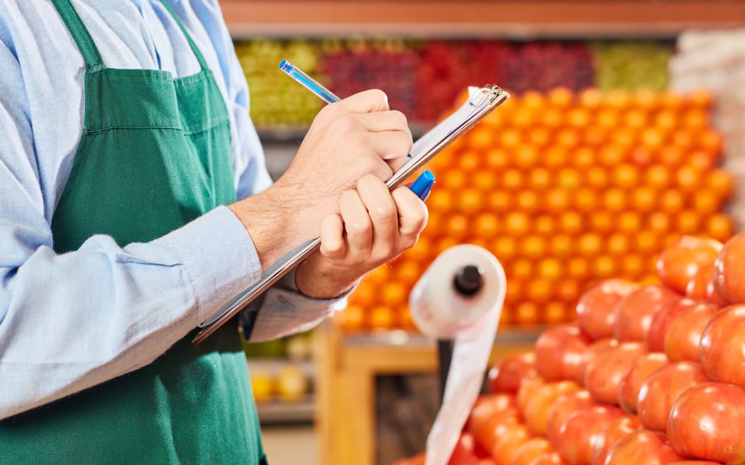 Businessman in the supermarket at inventory with checklist in the vegetable department
