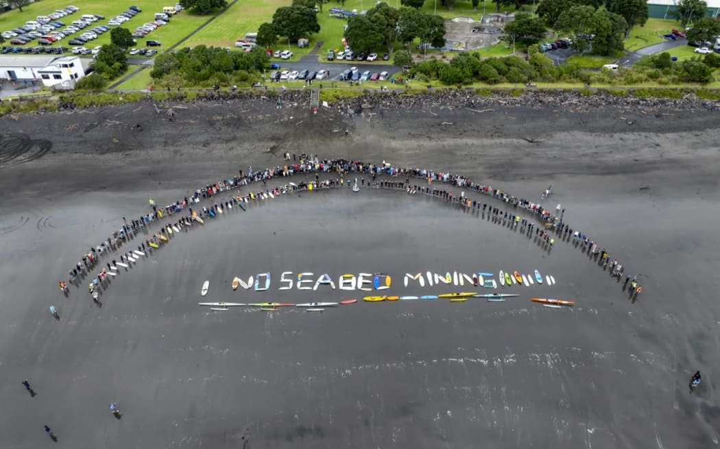 No seabed mining written on the beach with boards and canoes