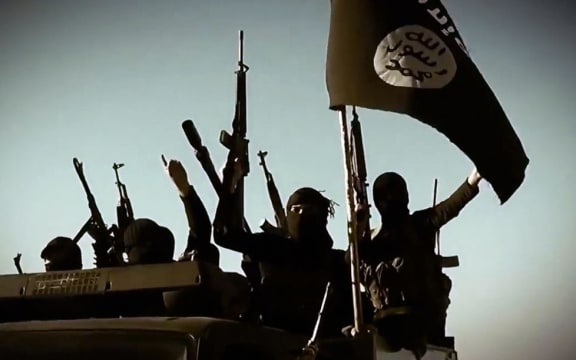 Alleged IS fighters raising their weapons as they stand on a vehicle mounted with the jihadists' trademark flag in Anbar province, Iraq.