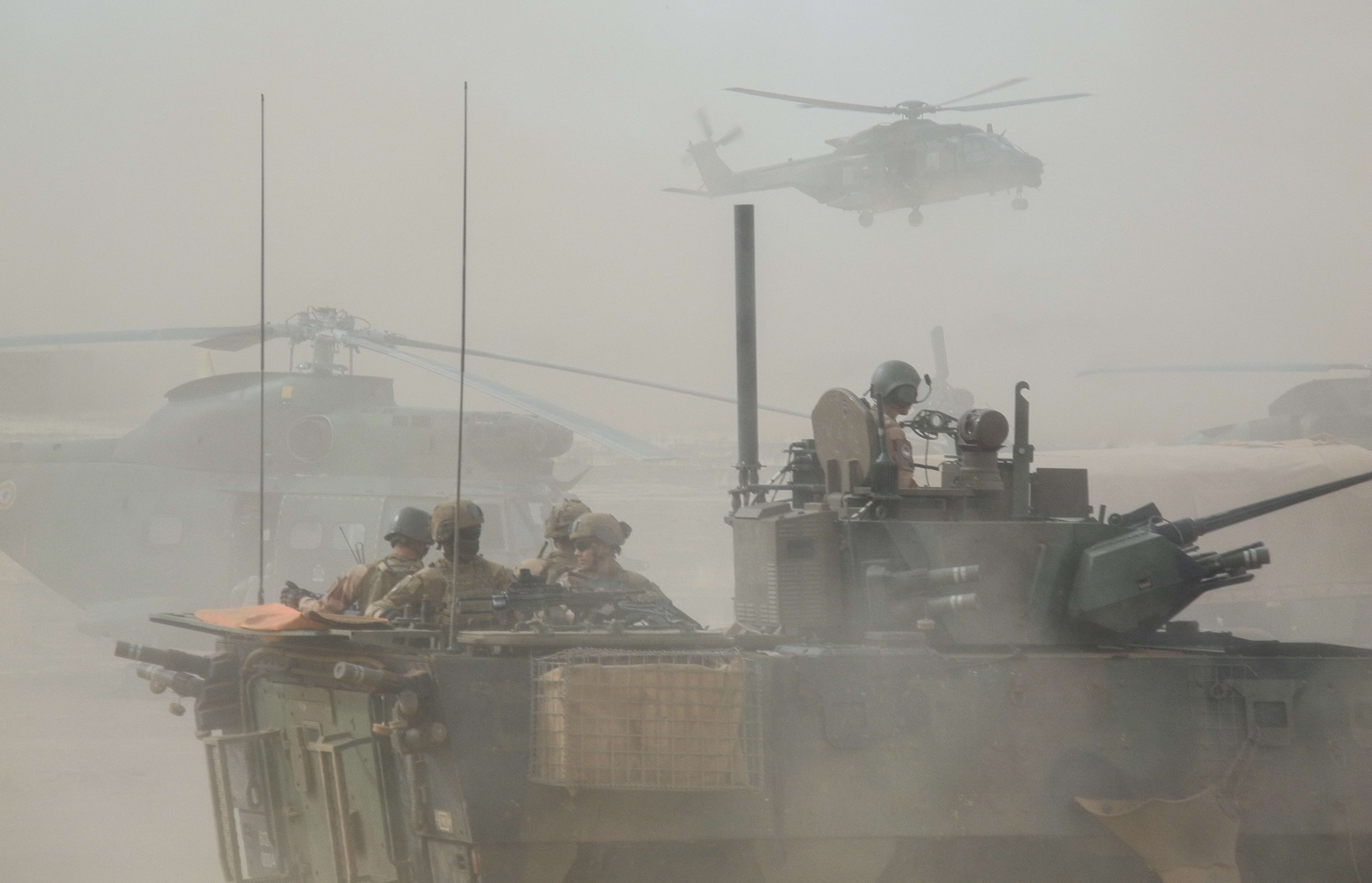 File photo taken on March 27, 2019 shows a French armoured vehicle driving by helicopters during the start of the French Barkhane Force operation in Mali's Gourma region.