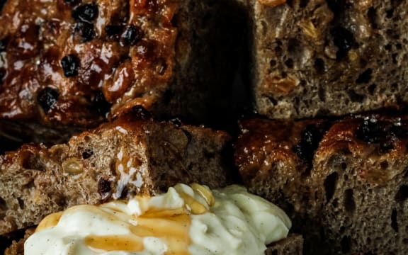 A stack of square pieces of fruit and spice-laden focaccia bread with an accompanying bowl of mascarpone