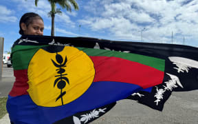 Woman wears Kanak flag with pride.