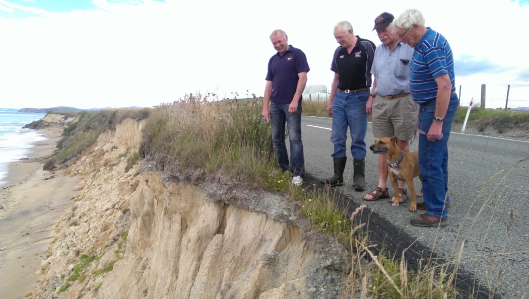 Residents survey the erosion that has partially closed the coastal route.
