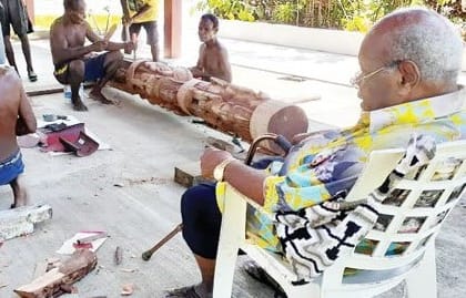 Sir Michael Somare, right, watches the carvers work on his 'special gift'.