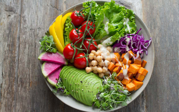 A vibrant bowl of salad vegetables, including avocado and chickpeas