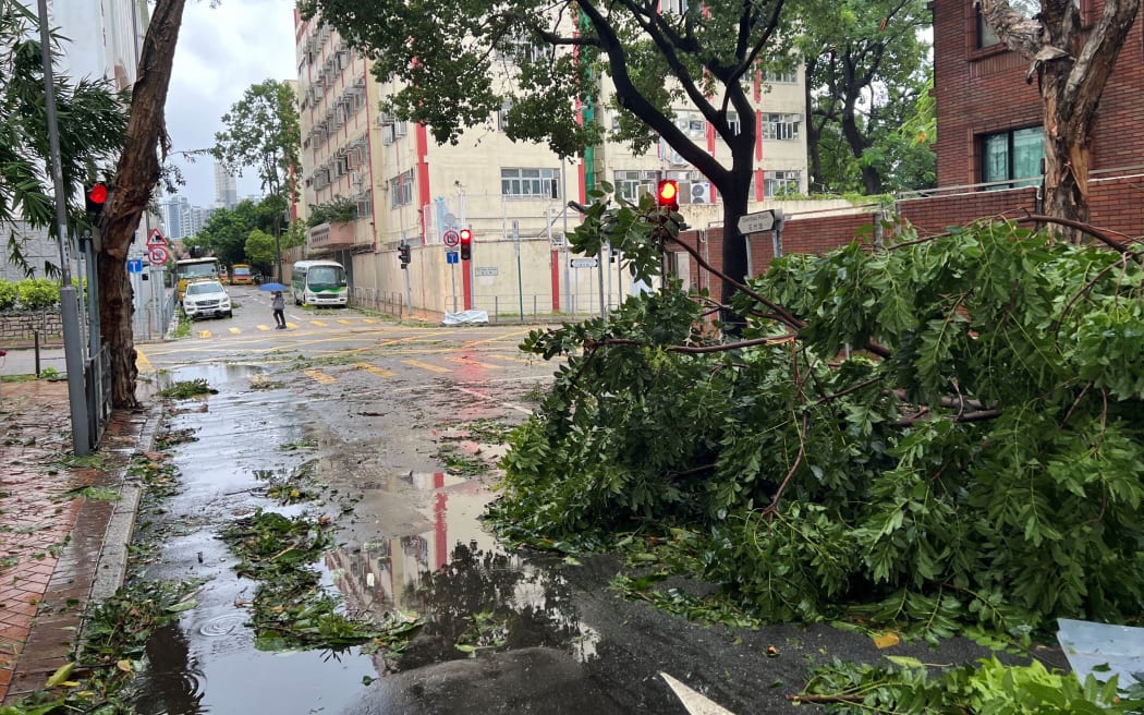 A pedestrian walks by damage caused by Super Typhoon Saola at the area of Kowloon Tong in Hong Kong on 2 September, 2023. Typhoon Saola swept across southern China on Saturday after tearing down trees and smashing windows in Hong Kong, although the megacity avoided a feared direct hit from one of the region's strongest storms in decades.