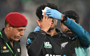 New Zealand's Rachin Ravindra (C) receives medical attention after being hit on the head by the ball during the Tri-Nation's first one-day international cricket match between Pakistan and New Zealand at the Gaddafi Stadium in Lahore on February 8, 2025.  (Photo by Farooq NAEEM / AFP)