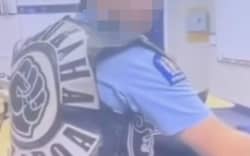 A screenshot of a Facebook post showing a police officer wearing a Mangu Kaha gang patch in the office.