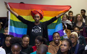 An activist holds up a rainbow flag to celebrate inside Botswana High Court in Gaborone on June 11, 2019. - Botswana's Court ruled on June 11 in favour of decriminalising homosexuality, handing down a landmark verdict greeted with joy by gay rights campaigners. (Photo by Tshekiso Tebalo / AFP)