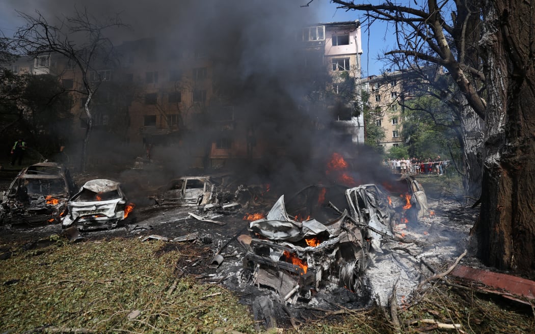 This photograph taken on July 8, 2024 shows burning cars at the site of a missile attack in Kyiv. Russia launched more than 40 missiles at several cities across Ukraine on July 8, 2024 in an attack that killed at least 20 people people and smashed into a children's hospital in Kyiv, officials said. (Photo by Anatolii STEPANOV / AFP)