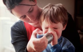 child taking asthma inhaler