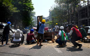 Protesters take cover behind makeshift barricades, made to obstruct security forces, during a demonstration against the military coup in Yangon on 28 February