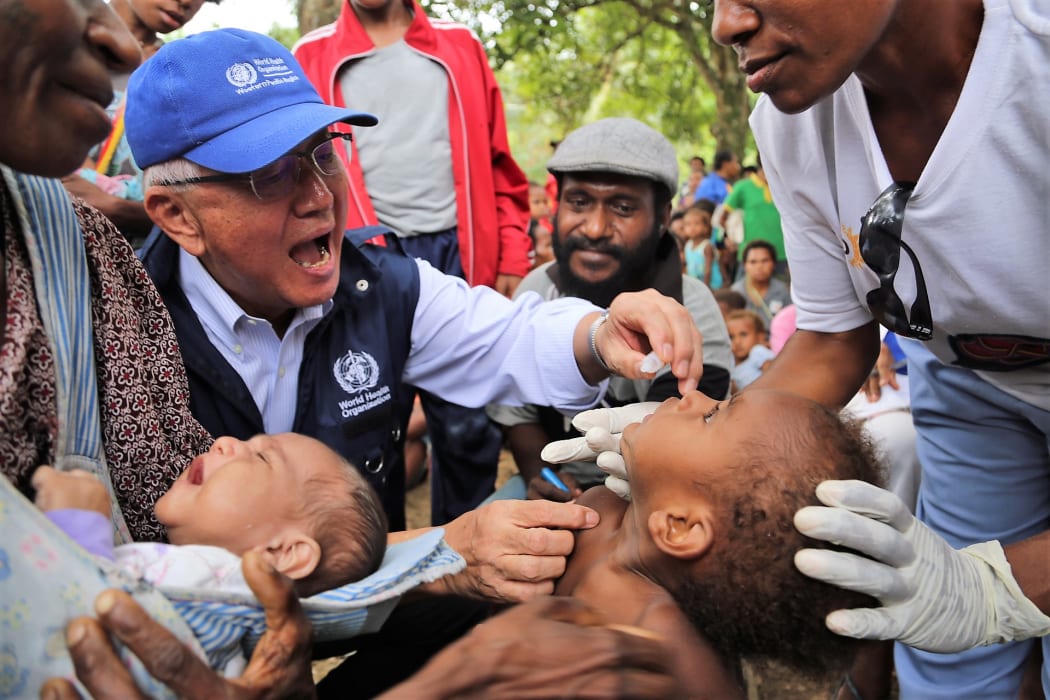 The WHO's Regional Director for the Pacific, Dr Shin Young-soo provides oral polio vaccine in Lae in Morobe