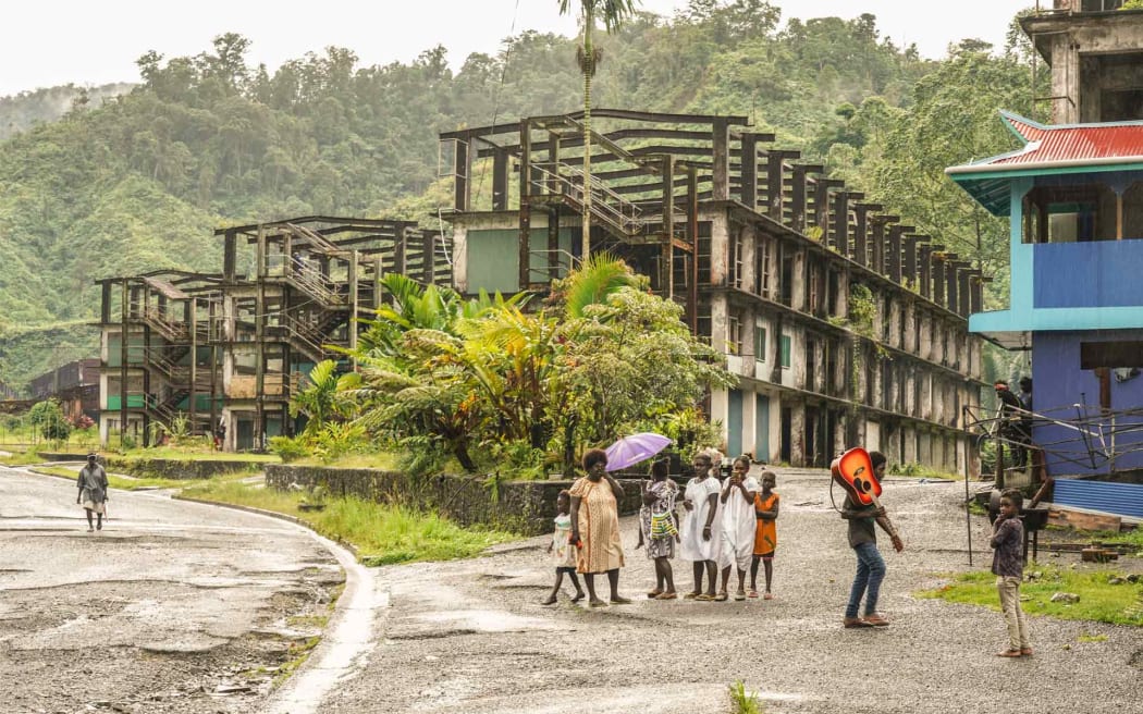 Locals walk by buildings left abandoned by a subsidiary of Rio Tinto at the Panguna mine site.