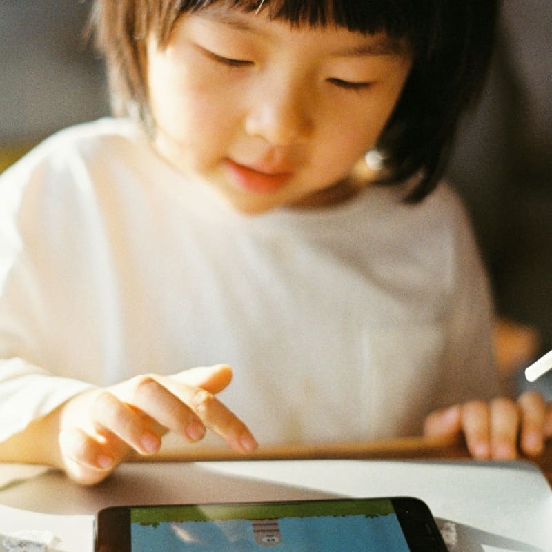An Asian girl touches a digital device.