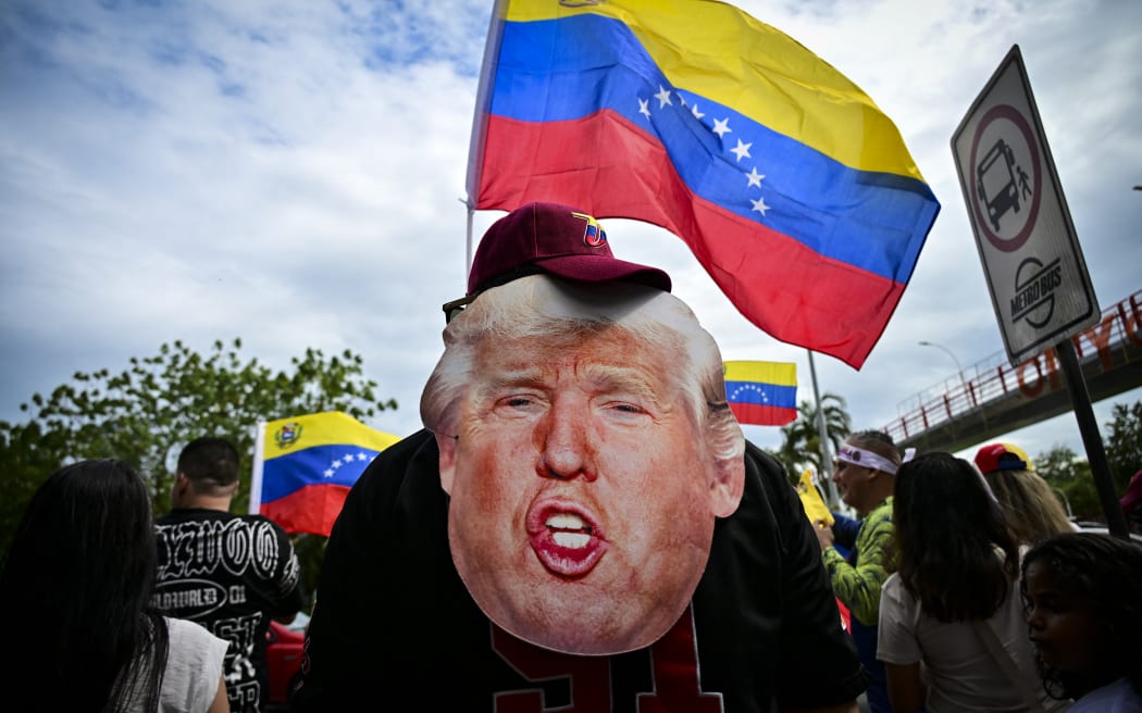 Venezuelans living in Panama celebrate with Venezuelan national flags and a mask depicting US President Donald Trump, in Panama City on January 3, 2026, after US forces captured Venezuelan leader Nicolas Maduro. President Donald Trump said Saturday that US forces had captured Venezuela's leader Nicolas Maduro after bombing the capital Caracas and other cities in a dramatic climax to a months-long standoff between Trump and his Venezuelan arch-foe. (Photo by MARTIN BERNETTI / AFP)