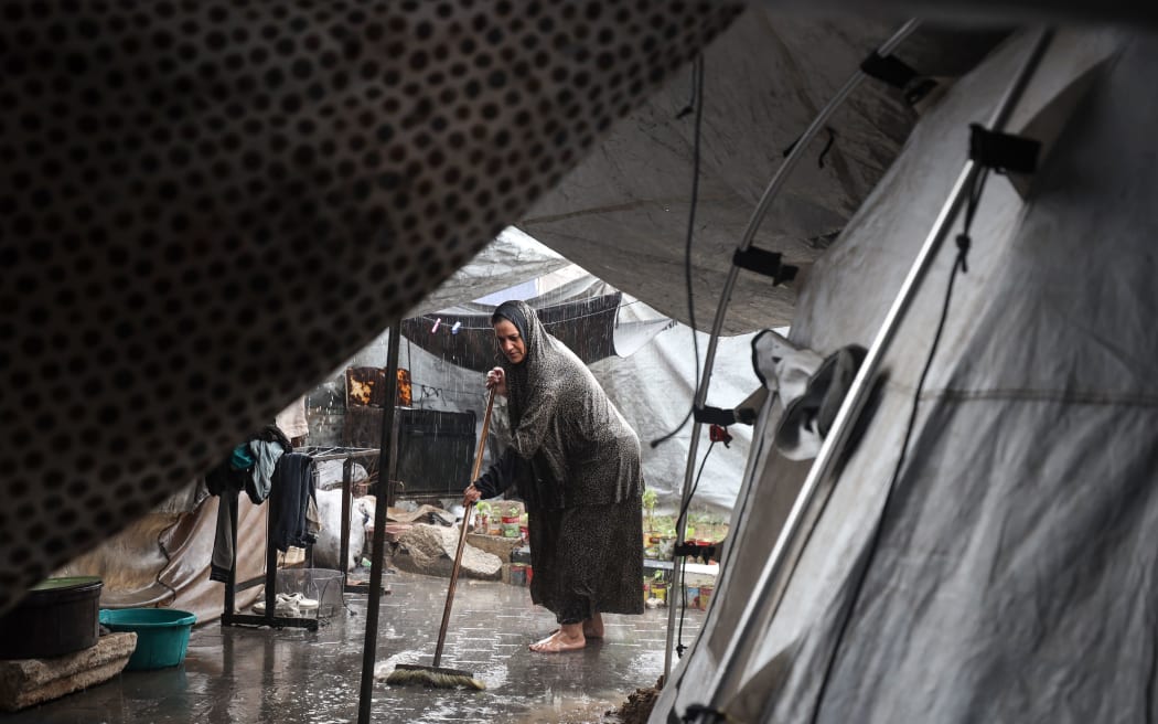 A Palestinian man clears stagnant water from the road near a displacement camp after the first winter rainfall in Gaza City on Friday.