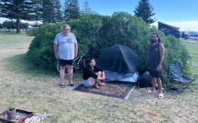 Stu Maylin, Trinity Tutaki-Epairama and Whare Wiki, who live in their vehicles. They are standing beside the tent belonging to homeless man 'Jimi' near a parking site on Marine Parade, Napier.