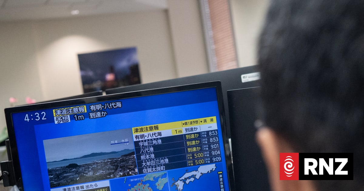 Reporters watch the news showing a large quake and possible one meter tsunami wave in Southern Japan, from an office in