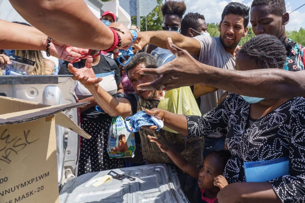 Migrants receive face masks near the Del Rio-Acuna Port of Entry.