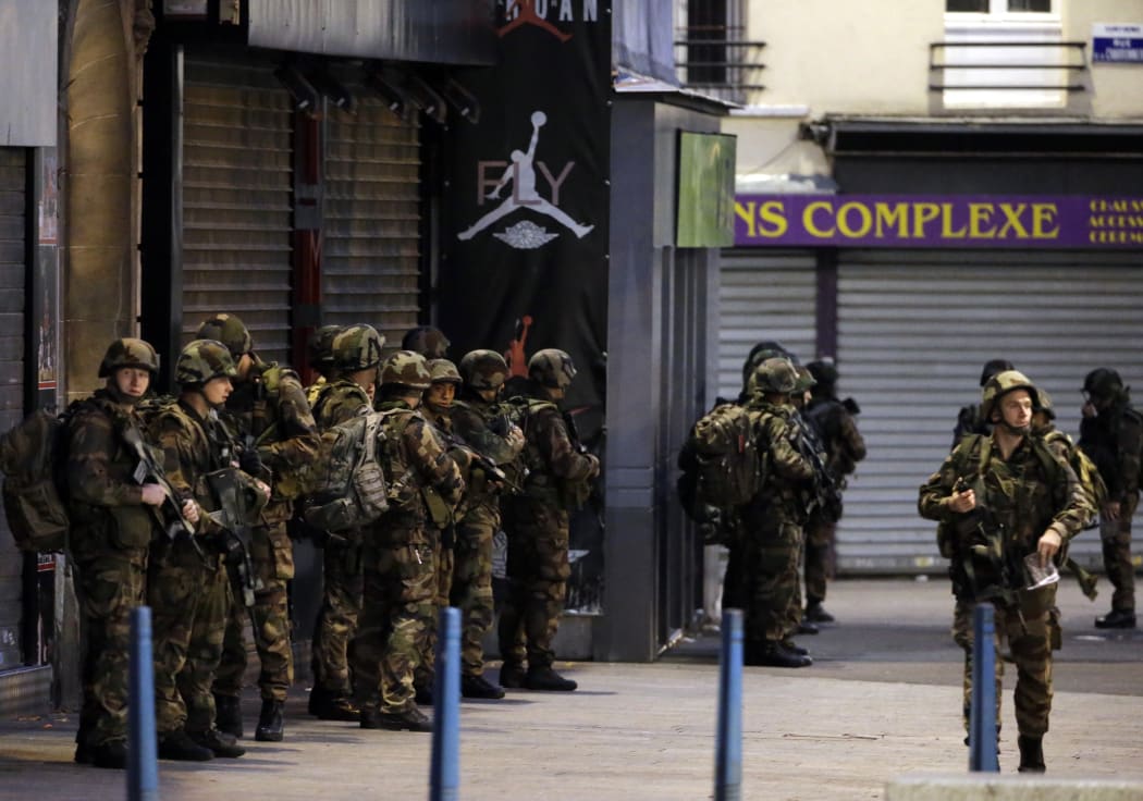 French army soldiers stand in position in the northern Paris suburb of Saint-Denis city center, on November 18, 2015, as French Police special forces raid an appartment, hunting those behind the attacks that claimed 129 lives in the French capital five days ago.