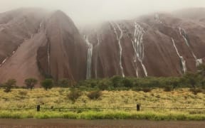 Waterfalls cascade down Uluru after flash flooding in central Australia