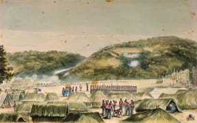 This painting by John Williams shows Ruapekapeka pā in the distance on a hill, with the smoke of gunfire around it. In the foreground on a flat area are British redcoats, some standing in line, some moving amongst raupo 'tents'.