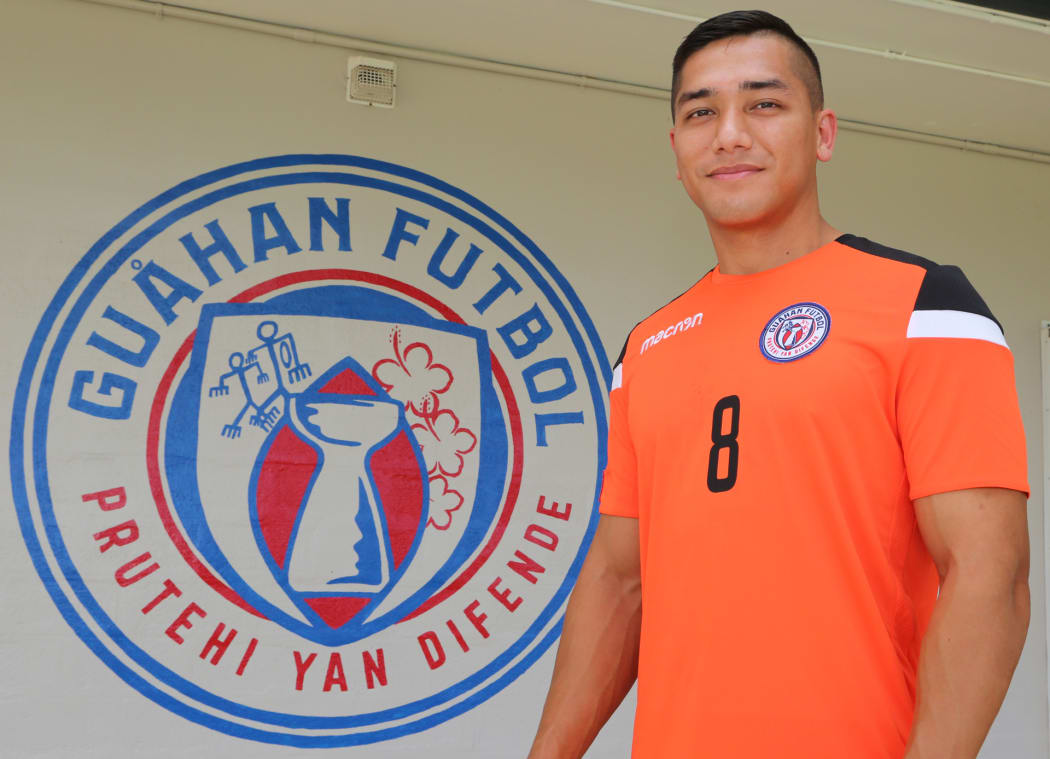Mark Chargualaf poses alongside the new Guam Football national team badge.