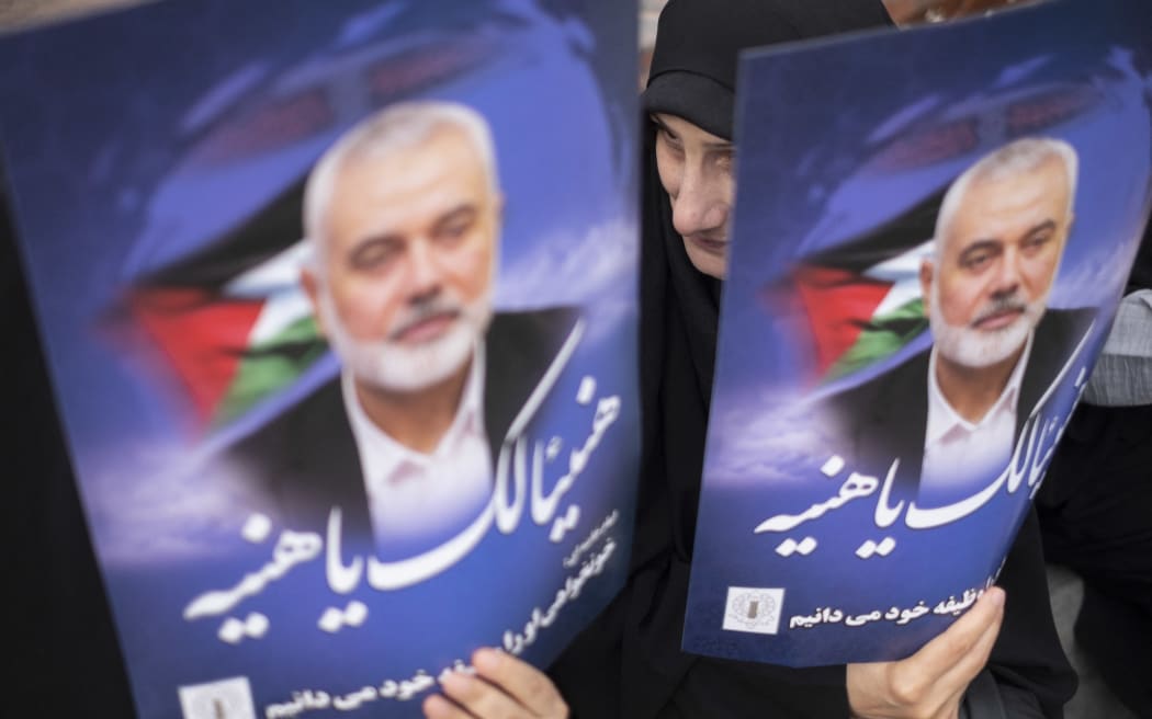 Iranian mourners are holding portraits of Hamas leader Ismail Haniyeh during a funeral ceremony for him and his bodyguard Abu Shaaban in Tehran, Iran, on August 1, 2024. Ismail Haniyeh and his bodyguard, Abu Shaaban, are being remembered after being killed in an air strike on Haniyeh's residence in northern Tehran the day after the inauguration ceremony of Iran's new president, Masoud Pezeshkian. (Photo by Morteza Nikoubazl/NurPhoto) (Photo by Morteza Nikoubazl / NurPhoto / NurPhoto via AFP)