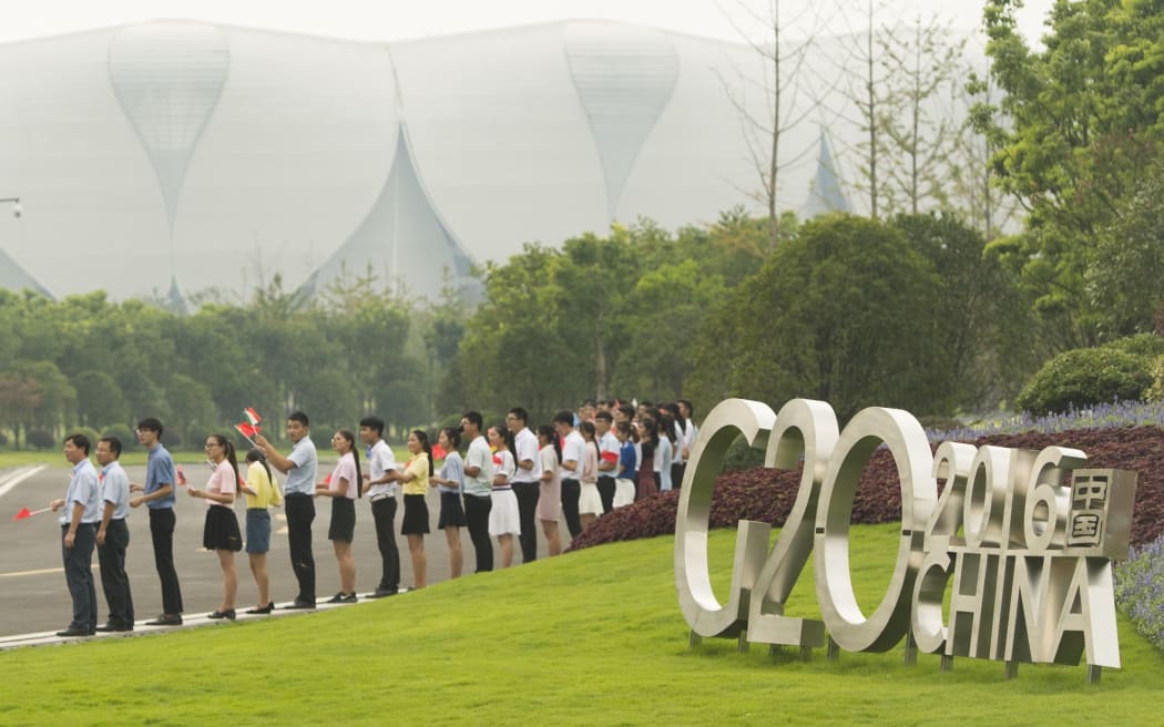 Wellwishers line up with flags to greet arriving leaders for the G20 Summit at the Hangzhou International Expo.